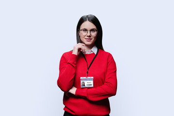 Portrait of young female teacher with badge on white background