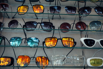 A showcase with a large number of fashionable sunglasses of different shapes with beautiful...