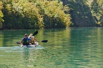 Fototapeta na wymiar A young couple enjoying an idyllic kayak ride in the middle of a beautiful river surrounded by forest greenery