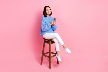 Photo of nice woman wear knit pullover hold smartphone sit on chair facebook twitter instagram...