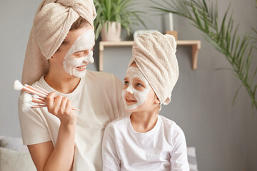 Attractive woman spending time with her kid doing cosmetic procedures and makeup together mother...