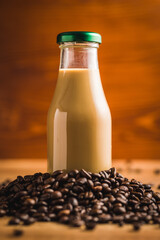 Coffee milk in glass bottle and coffee beans on wooden table.