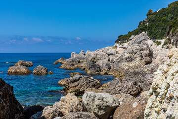 A beautiful landscape of the coast of the island of Corfu in the Ionian Sea of the Mediterranean in Greece. Pure blue clear water washes over the shores of the Greek island.