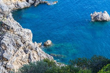 A beautiful landscape of the coast of the island of Corfu in the Ionian Sea of the Mediterranean in Greece. Pure blue clear water washes over the shores of the Greek island.