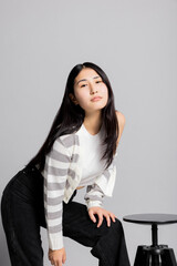 Serious concentrated young asian woman in fashionable stylish clotes looking at camera posing in...