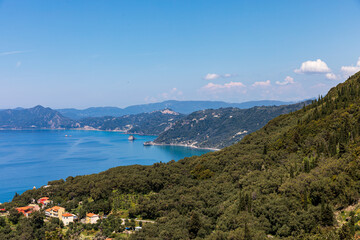 Fototapeta na wymiar A beautiful landscape of the coast of the island of Corfu in the Ionian Sea of the Mediterranean in Greece. Pure blue clear water washes over the shores of the Greek island.