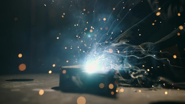 The man is welding. Welding with argon or electrode, using a welding machine. Sparks and flashes fly.