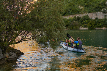 Fototapeta na wymiar A young couple enjoying an idyllic kayak ride in the middle of a beautiful river surrounded by forest greenery