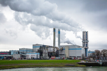 Fototapeta na wymiar An industrial plant with chimneys from which thick smoke comes out into a cloudy sky. Environmental pollution by industry.