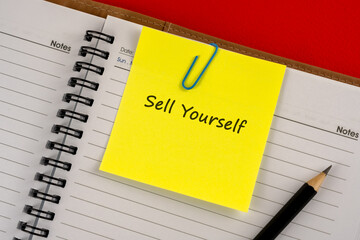 Sell yourself text on adhesive note clipped on note pad