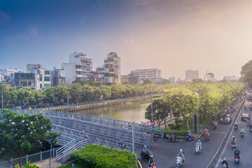 Busy traffic during sunset and night, colorful perspective of Ho Chi Minh city with numerous hotel, bar and shop sign boards, crowded with people, motorbikes
