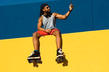 Black man taking selfie photo outside. Urban man posing with roller skates.