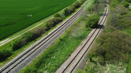 Fototapeta na wymiar train railways running through the green wheat field, drone photography