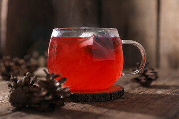 Tea with herbs, berries and fruits in a transparent cup on a wooden background