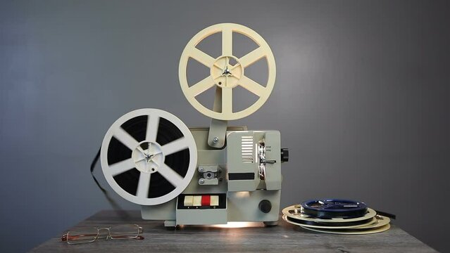 The retro movie projector has finished showing the film. The end of the film. Old film projector, side view, on a gray background.