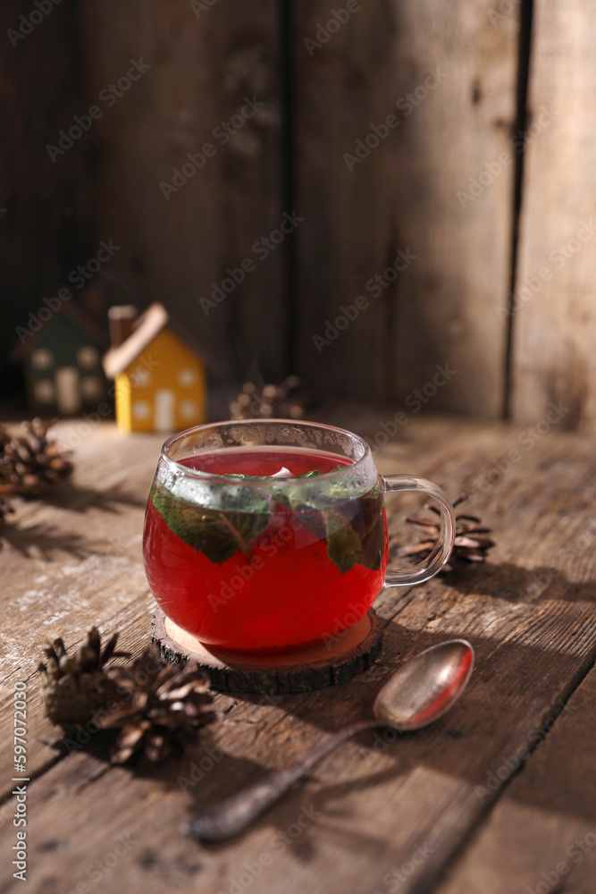 Wall mural tea with herbs, berries and fruits in a transparent cup on a wooden background