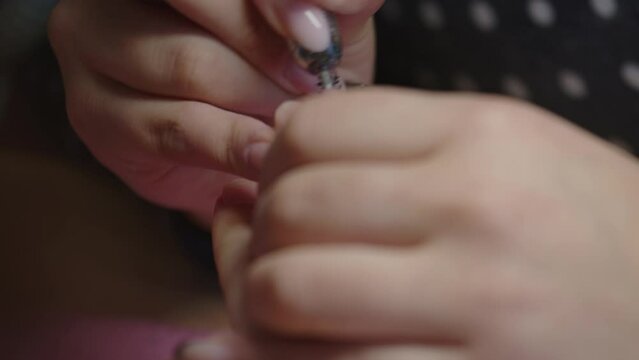 Manicurist removes gel polish with nail drill manicure tool. Close up shot. 