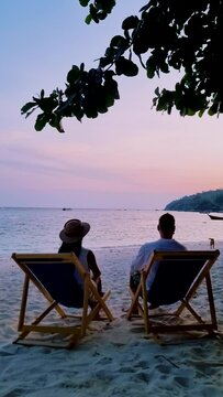 couple of men and women relaxing on a beach chair during sunset on the beach of Koh Lipe Thailand