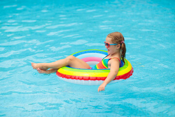 Fototapeta na wymiar Child in swimming pool on toy ring. Kids swim.