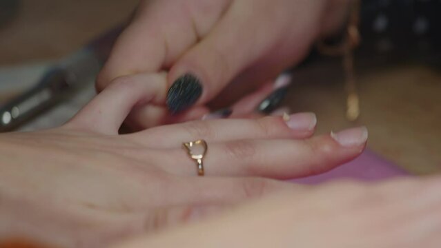 Female manicurist massaging cuticle oil into skin around fingernails, close up