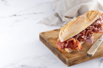 Spanish serrano ham sandwich on marble background. Copy space