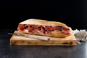 Spanish serrano ham sandwich on black slate background
