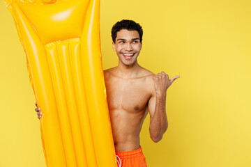 Young man wear orange shorts swimsuit relax near hotel pool hold in hand inflatable mattress point...