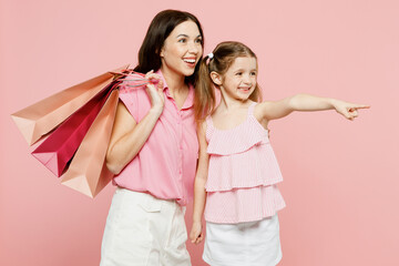 Young fun woman wear casual clothes with child kid girl 6-7 years old hold shopping package bags. Mother daughter isolated on plain pink background. Black Friday sale buy day, family parent concept.