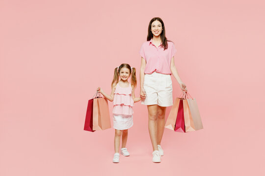 Full body young woman wear casual clothes with child kid girl 6-7 years old hold shopping bag go. Mother daughter isolated on plain pink background. Black Friday sale buy day, family parent concept.