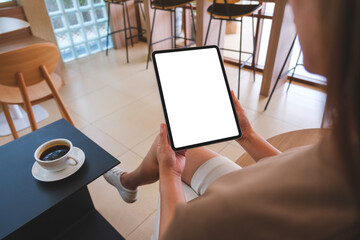 Mockup image of a woman holding digital tablet with blank white desktop screen in cafe