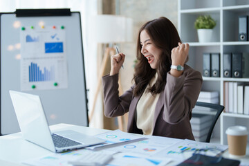 Beautiful young teen asian businesswomen using computer laptop with hands up in winner is gesture, Happy to be successful celebrating achievement success