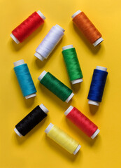 Multicolored sewing threads on a yellow background. Top view.