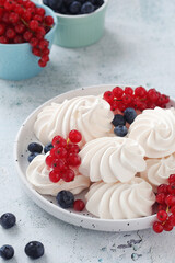 White sweet traditional merenques with berries on the plate