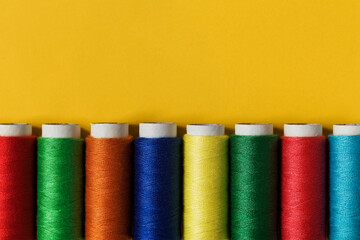 Set of colorful sewing treads on a yellow background. Top view. Copy space.
