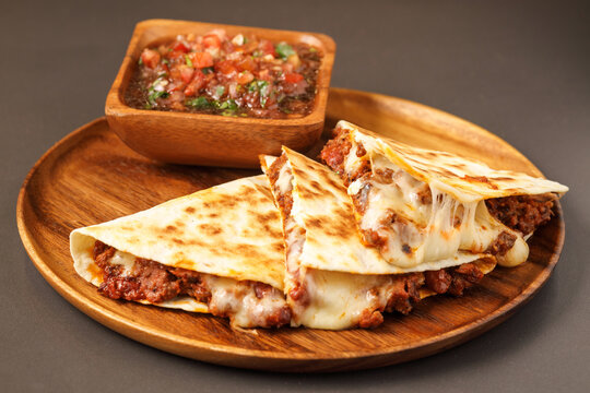 Quesadillas with cheese and salsa served on wooden plate, Mexican food