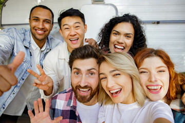 Mixed race friends taking selfie on mobile phone, outdoor party on travel trailer background. Rest outside the city. Happy people enjoy. Weekends in the summer time.