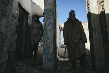 A man and a woman in a destroyed building, with gas masks, come out of different rooms