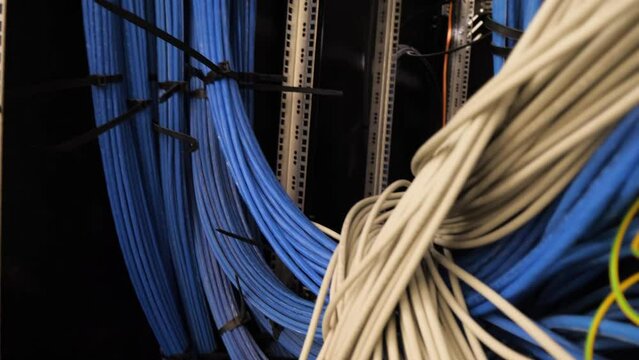 Close-up of a complex network server filled with blue electrical wiring and communication cables for internet, transmitting data and information over the 10GB 100GB/TB networks.