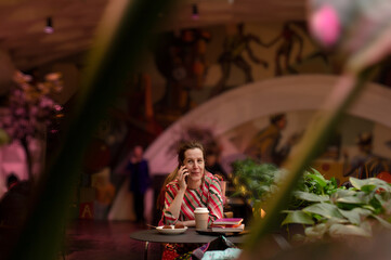 Fototapeta na wymiar Woman sitting in cafe alone and talking on the phone