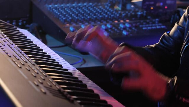 Male hands playing on piano electronic keyboard. Colorful stage lighting Fingers tapping drum pads midi controller. Sound maker create music melody.