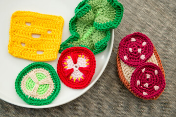 Handmade crochet sandwich with sausage, salad, cheese, cucumber and tomato. Healthy breakfast, kitchen toys for preschool children. Sensory cooking games at home, to develop kids imagination.