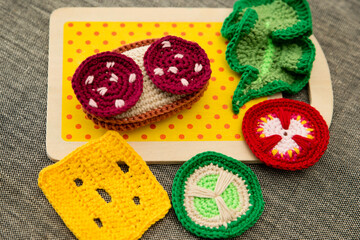 Handmade crochet sandwich with sausage, salad, cheese, cucumber and tomato. Healthy breakfast, kitchen toys for preschool children. Sensory cooking games at home, to develop kids imagination.
