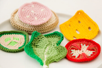 Handmade crochet sandwich with sausage, salad, cheese, cucumber and tomato. Healthy breakfast, kitchen toys for preschool children. Sensory cooking games at home, to develop kids imagination.