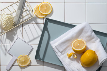 A basket with scalp massage brush and a comb arranged with a mirror and a tray of towel and Lemons....