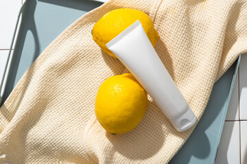 A pastel tray with a towel and empty label white tube displayed on. The vitamin C in Lemon (Citrus...