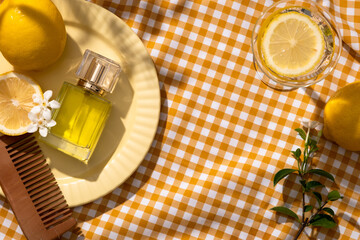 A dish displayed a wooden comb, white flowers and unbranded perfume glass bottle. Decorated with a glass with Lemon slice. Essential oil extracted from Lemon is an ingredient for fragrance production