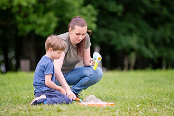 Mom and son are playing in the park. Cheerful happy family having a picnic. Vacations and trips out of town in country.