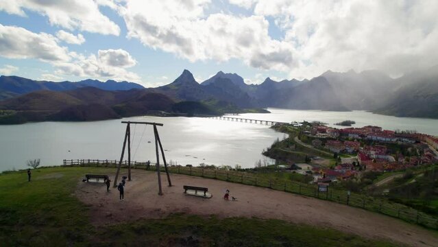 Static aerial shot with parents swinging their child on the swing at the viewpoint in Ria&ntilde;o, a village in Le&oacute;n, Spain on the shore of a large reservoir in the Cantabrian mountains.
