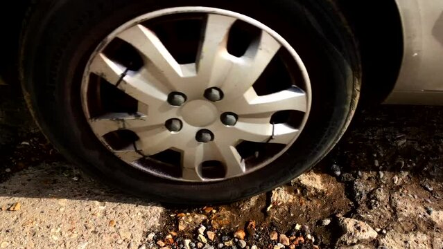 Giant pothole in roadway full of water - car passes over.