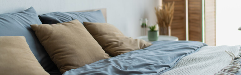 Pillows and blanket on bed in blurred bedroom, banner.